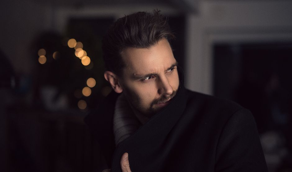Portrait of a handsome man in a coat indoors with creative lighting and bokeh effect.