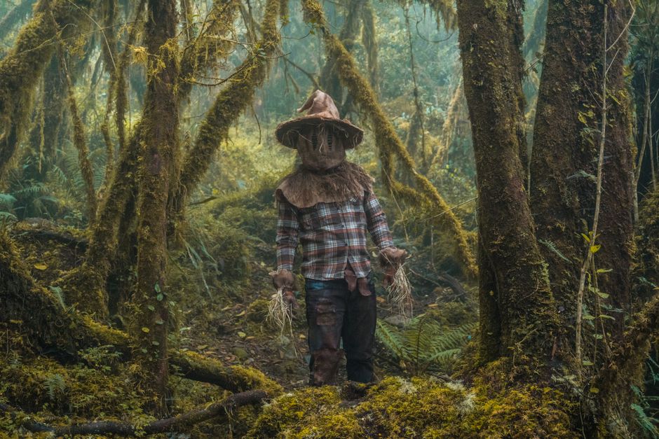A mysterious figure wearing a costume stands in a misty forest in Choachí, Colombia.
