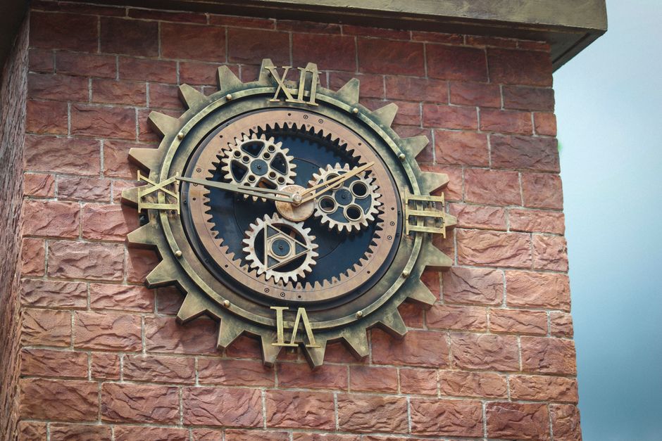 Close-up of a steampunk clock tower displaying intricate gear mechanisms on a brick wall.