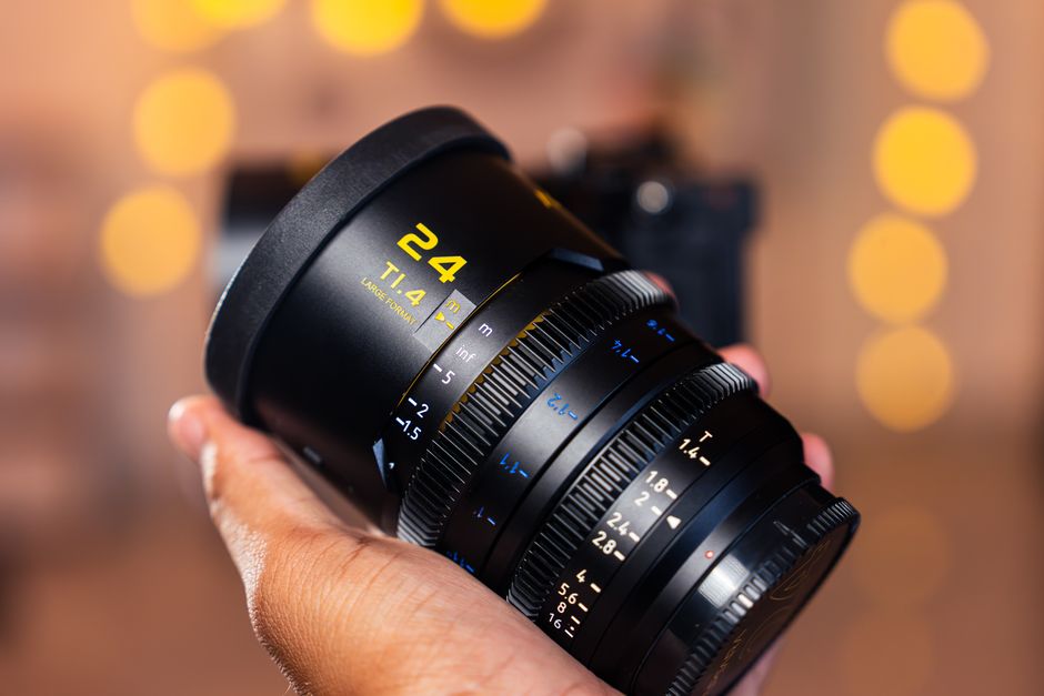 Detailed shot of a camera lens held in hand with a soft bokeh background, emphasizing precision and photography equipment.